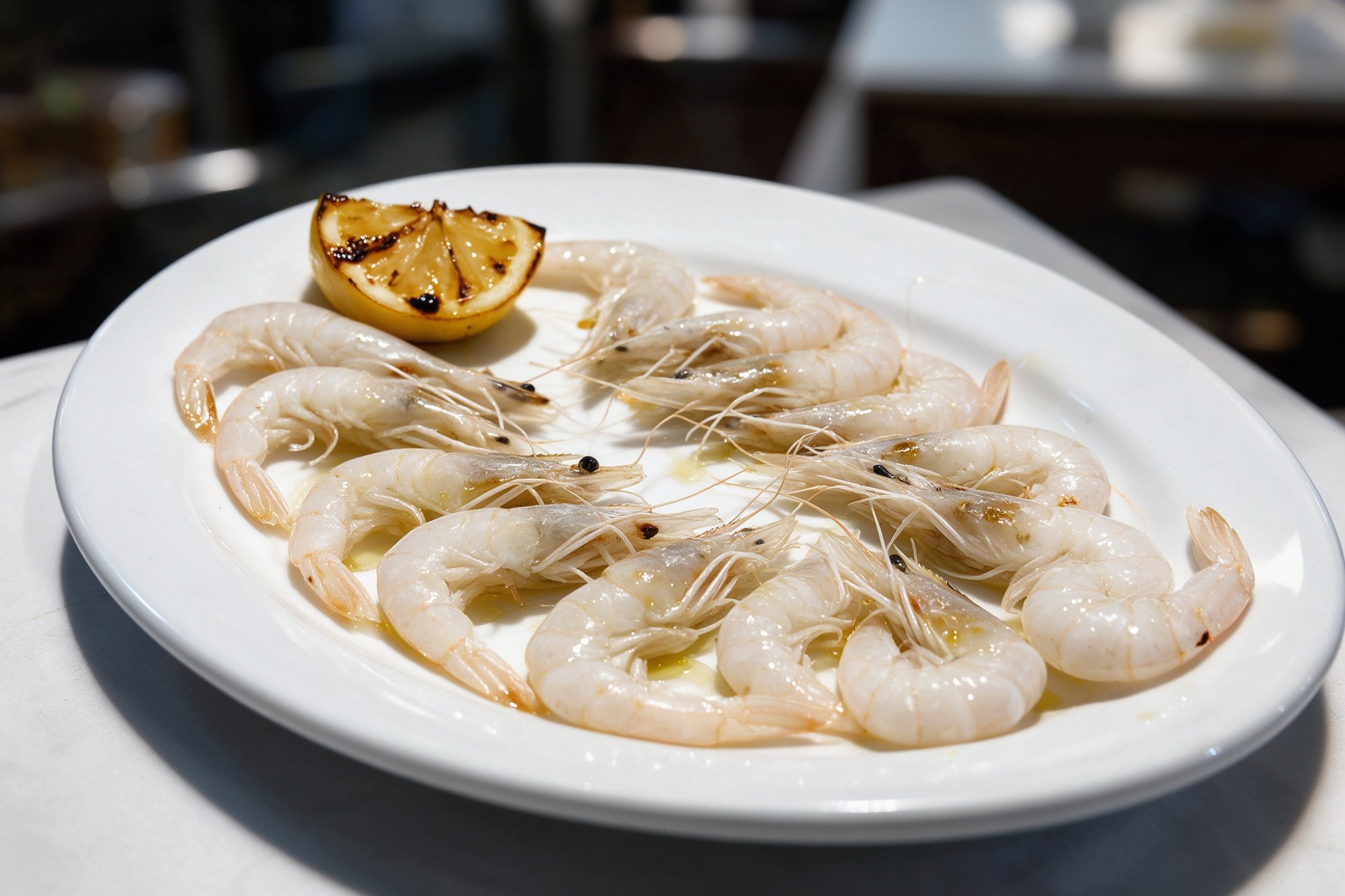 Plato ovalado blanco de gambas cristal a la plancha con limón en restaurante de El Palo